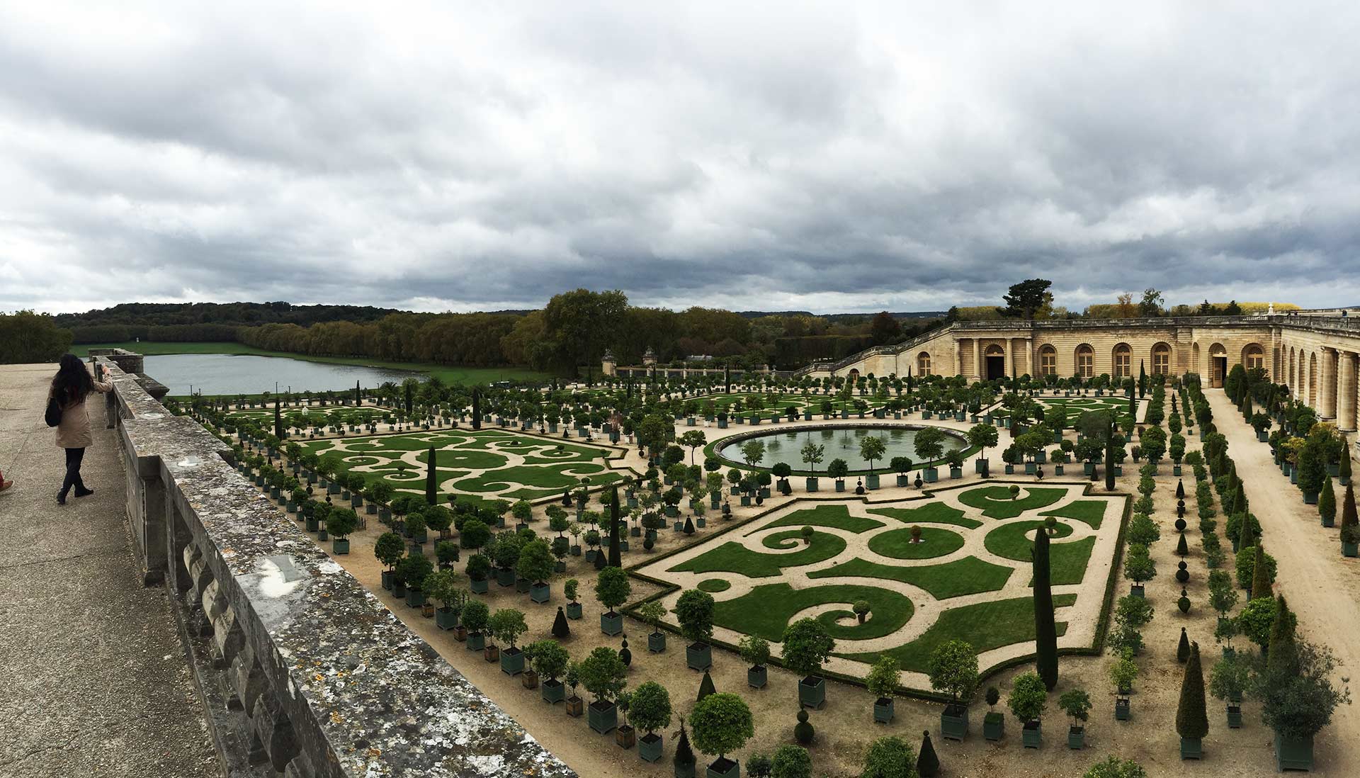 The Orangerie of Versailles on a cloudy day with Corinne on the left
